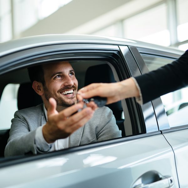 Portrait of happy young customer buying new car