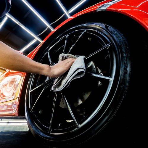 Car service worker polishing car wheels with microfiber cloth. Tools for polishing